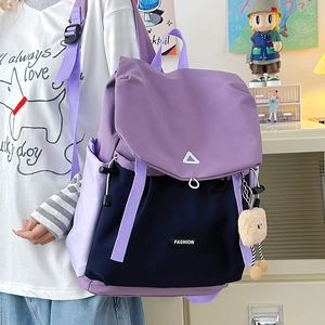Side view of blue and purple hiking backpack with flap closure and cute plush monster charm