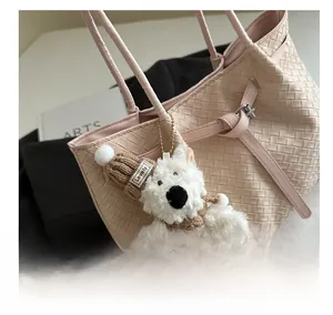 Detail of a white plush charm with a brown knit hat on a pink woven tote bag