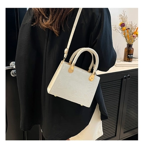 Detail showing the elegant floral embossed texture and braided handle of the off-white bag