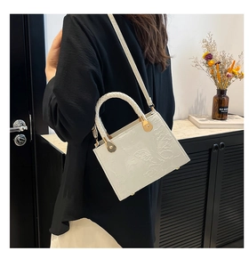 Detail showing white handbag with 3D floral embossing and woven top handle for women