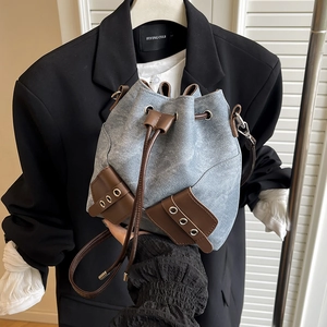 Vintage denim bucket bag with leather trim and drawstring closure held by a model