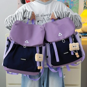 Detail view of purple and navy color-blocked backpack with cute plush square charms