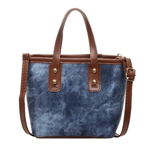 Vintage denim handbag with brown leather trim and golden rivets in a front view