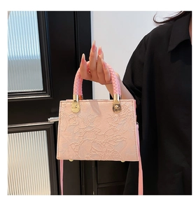 Detail of pink handbag featuring 3D embossed floral patterns and woven leather handle