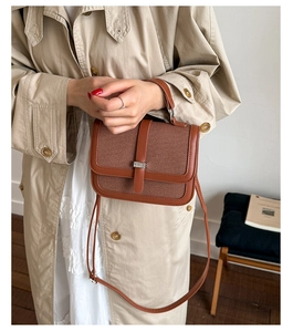 Close-up of caramel brown woven crossbody bag with leather trim and metallic buckle