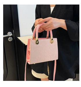 Detailed view of pink square handbag featuring 3D floral texture and braided top handle