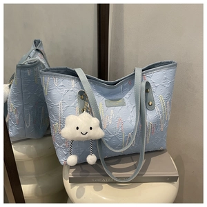 Detail of light blue textured tote bag with wave stitching and cloud plush charm