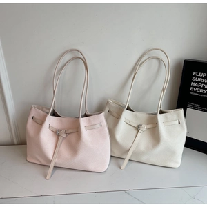 Détail de cabas élégants à texture tissée en rose tendre et beige sur surface de marbre