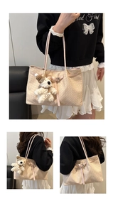 Detail of light beige woven tote bag featuring leather straps and a cute plush bear charm