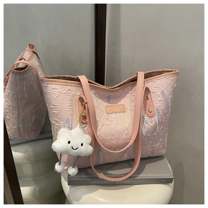Detailed macro view of pink embossed tote bag with stripe embroidery and cloud charm