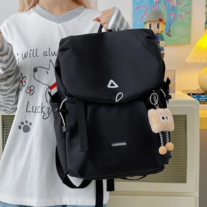 Detail of waterproof nylon backpack featuring flap closure and plush charm accessory