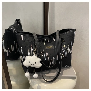 Detail of striped canvas tote with wave embroidery and cute plush cloud pendant charm