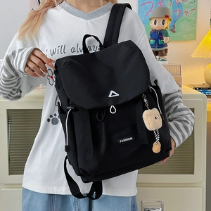 Detail of black outdoor backpack featuring drawstring closure and cute plush accessory