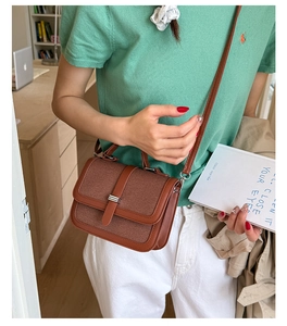 Detail of caramel brown woven crossbody bag with leather trim and metal bar buckle