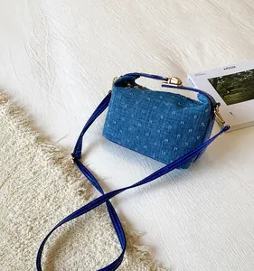 Detail der blauen Denim-Quadrat-Tasche mit 3D-Bogenknoten-Webtextur und goldenen Beschlägen