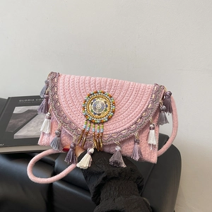 Pink bohemian woven straw crossbody bag with colorful tassels and floral bead detail