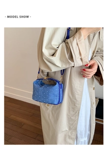Blaue Denim-Umhängetasche von einem Model vor einem minimalistischen Wandhintergrund