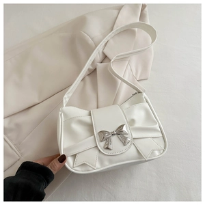 Detail of the oversized bow and silver metallic clasp on a cream leather shoulder bag
