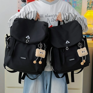 Detail of black nylon backpack with flap closure and cute plush toast charm accessory