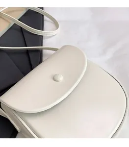 Detail view of cream saddle bag with matte PU leather finish and magnetic flap closure