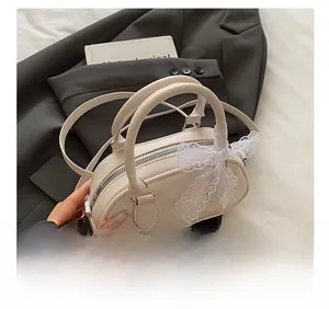 Dettaglio borsa Boston bianca goffrata con fiocco in pizzo e tracolla in pelle PU