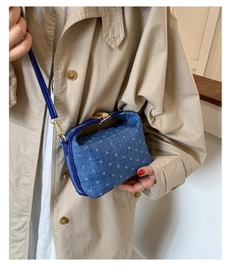 Detail of denim blue crossbody bag with monogram texture and gold metal buckle closure