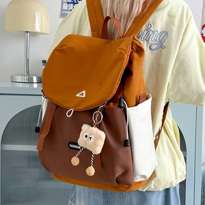 Detail of color-block hiking backpack with drawstring closure and plush monster charm