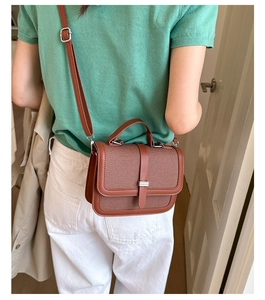 Detail of a brown crossbody bag featuring woven texture and silver hardware accents