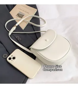 Detail view of cream saddle bag next to a smartphone showing small size comparison