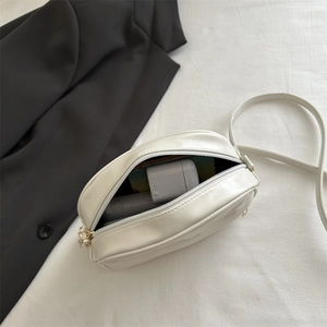 Minimalist white leather crossbody bag with adjustable strap and top zipper closure