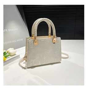Detail of white tote bag with floral embossed texture and braided leather handles