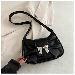 Detail of black pleated shoulder bag with silver metallic bow buckle on textured fabric