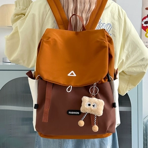 Detail of outdoor backpack featuring color-block design and cute plush toy charm