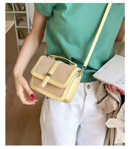 Detail of vintage beige straw and PU leather crossbody bag worn by a model in green