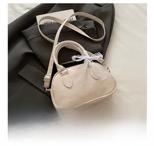 Borsa bowling crema con motivi a rilievo e fiocco di pizzo su un blazer nero