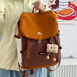 Detail of color-block backpack featuring orange and brown nylon with plush charm