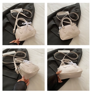 Dettaglio della borsa a cuscino crema con goffratura a cuore e fiocco in pizzo decorativo