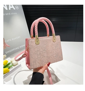 Detail of pink embroidered handbag featuring floral texture and woven leather handle