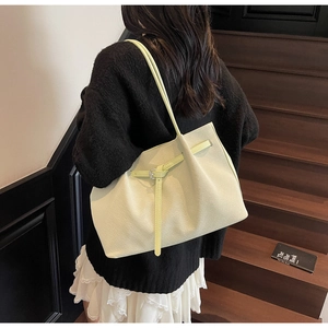 Gros plan du sac cabas vert clair à texture tissée et détail de boucle sur modèle