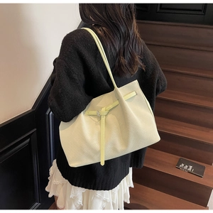 Détail du sac fourre-tout vert clair à texture tissée avec boucle sur un escalier