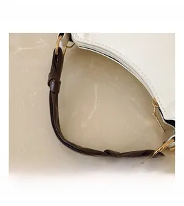 Détail d'un sac blanc avec poignée nouée marron et anneaux en D dorés sophistiqués