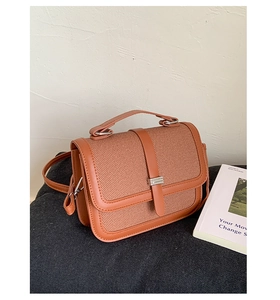 Detail of a brown leather and fabric handbag with a vintage textured finish and silver buckle