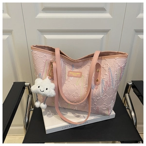 Detail of pink canvas tote featuring colorful wavy embroidery and a cute cloud pendant