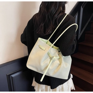 Gros plan d'un sac seau tressé vert clair avec détails de sangle sur le mannequin