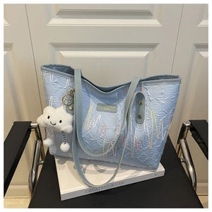 Close-up of light blue canvas tote bag with letter jacquard and cloud pendant