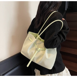 Détail du sac cabas vert clair avec texture tissée et boucle en métal sur l'escalier