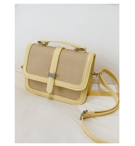 Detail of summer handbag featuring beige woven texture and yellow faux leather trim