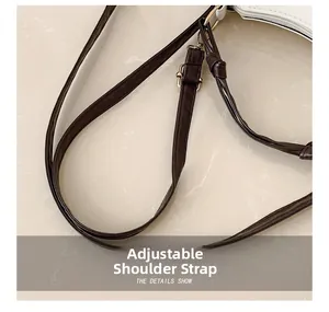 Détail d'une bandoulière réglable en cuir marron foncé avec boucles en métal doré