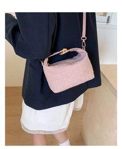 Close-up of pink textured crossbody bag with gold hardware worn by a model in a suit