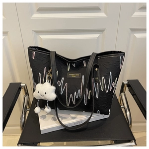 Detail of black tote bag featuring colorful wavy stitching and a cloud plush pendant